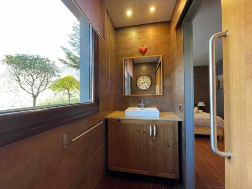 La salle de bains est pourvue d'un lavabo et d'une fenêtre avec une horloge. dans l'établissement Casita dúplex en Casa Rural Camp de Claror, à Sant Julià de Lòria
