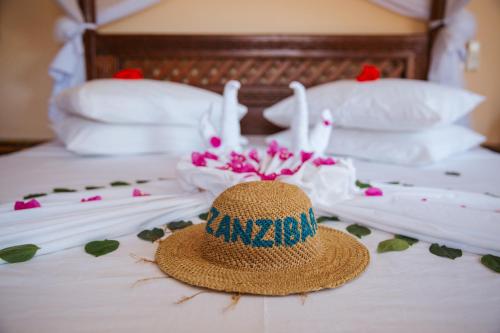a straw hat sitting on top of a bed with flowers at Mambo Paradise in Matemwe