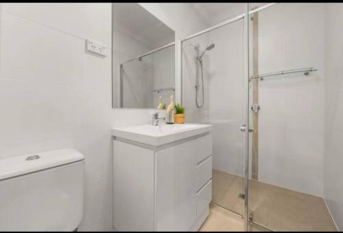 a white bathroom with a sink and a shower at Entire lovely house with 3 bedrooms, good location in Hall