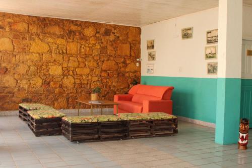 a waiting room with a red chair and a table at Pousada Vila do Penedo in Penedo
