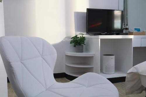 a white living room with a white chair and a tv at Party& Dream Homestay in Kenting