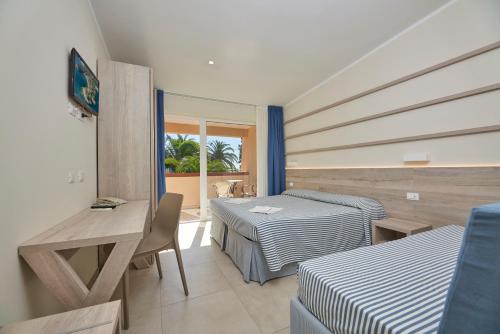 a room with two beds and a table and a window at Hotel Villa Rodriguez in Capoliveri