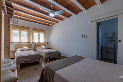 1 dormitorio con 2 camas en una habitación con techos de madera en Cal Xot, en El Poblenou del Delta