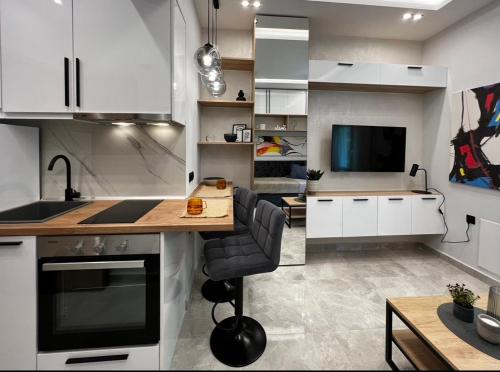 uma cozinha com armários brancos e um banco de bar preto em ARES SUITE em Tessalônica