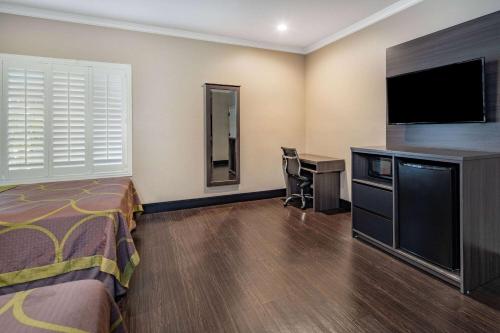 a hotel room with a bed and a desk and a television at Super 8 by Wyndham North Hollywood in North Hollywood