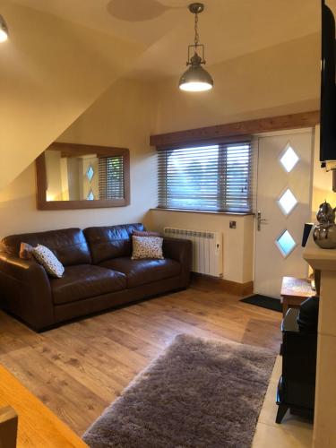 a living room with a leather couch and a window at Tar Top in Silsden