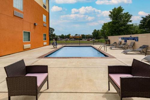 a pool in a courtyard with chairs and a building at Days Inn & Suites by Wyndham Horn Lake - Memphis Graceland in Horn Lake