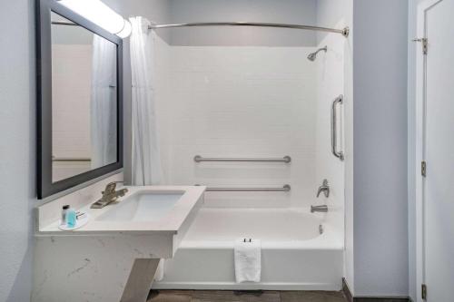 Baño blanco con lavabo y espejo en Days Inn & Suites by Wyndham Horn Lake - Memphis Graceland en Horn Lake