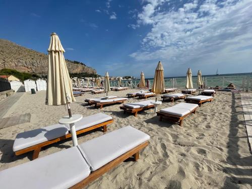 a bunch of lounge chairs and umbrellas on a beach at AWA Mondello in Mondello