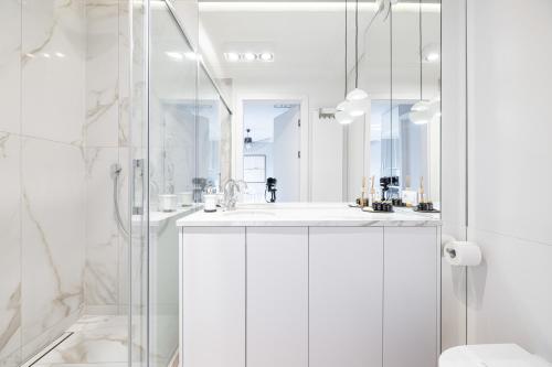 a white bathroom with a shower and a sink at GREAT Grano Residence in Gdańsk