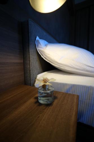 a glass jar with a flower on a table next to a bed at Woodside TEA Residences & SPA Kopaonik in Kopaonik