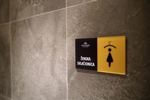 a yellow sign on a wall in a bathroom at Woodside TEA Residences & SPA Kopaonik in Kopaonik