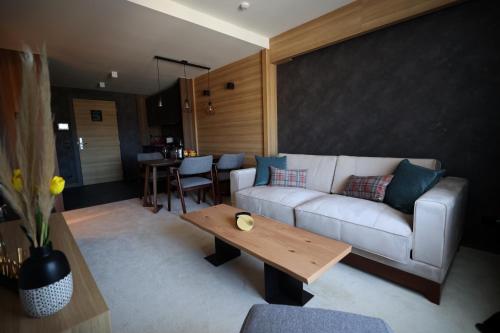 a living room with a white couch and a wooden table at Woodside TEA Residences & SPA Kopaonik in Kopaonik