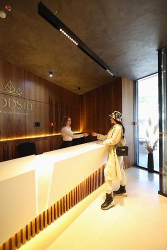 a woman is standing at a counter in a lobby at Woodside TEA Residences & SPA Kopaonik in Kopaonik