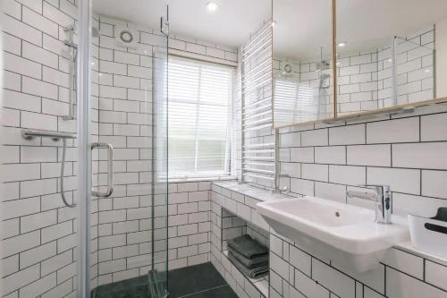 a white tiled bathroom with a sink and a shower at The Brew House in Bath