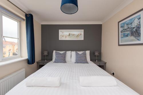 a bedroom with a large white bed with blue curtains at Hillbrook in Thornaby on Tees
