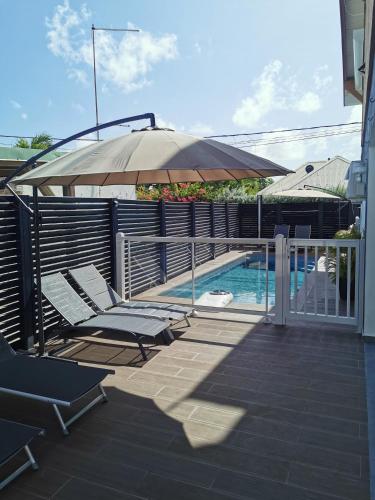 a patio with chairs and an umbrella next to a swimming pool at L'améthyste in Saint-François
