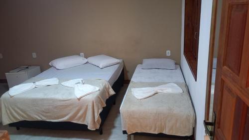 two beds in a room with towels on them at Pousada Cordel de Itaúnas in Itaúnas
