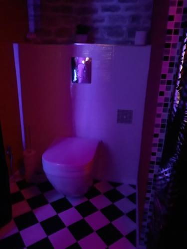 a bathroom with a toilet in a purple light at LOVE ROOM Le rouge et noir in Barr