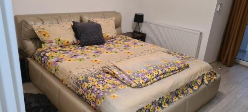 een bed met een bloemendeken en kussens erop bij Apartament cu 1 camera spatios ,luminos . in Cugir