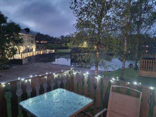a patio with a table and a fence with lights at 4 Bed Luxury Lodge with Hot tub near Lake District in Warton