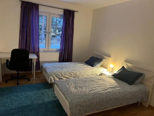 a bedroom with two beds and a window with purple curtains at Beautiful terraced house with private parking in Sandviken