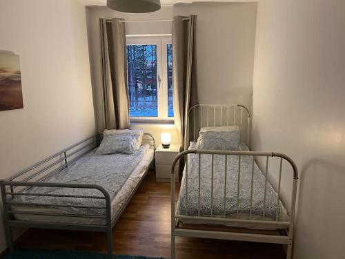 2 camas en una habitación pequeña con ventana en Beautiful terraced house with private parking, en Sandviken