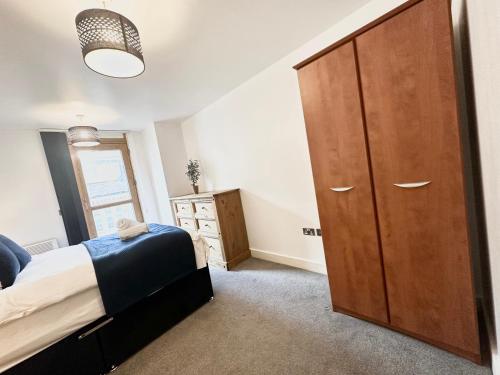 a bedroom with a large wooden cabinet and a bed at The Temple House Balcony Suite in Birmingham