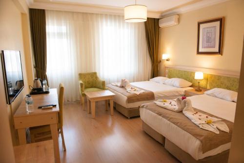 a hotel room with two beds and a desk at Hotel Simsek in Edirne