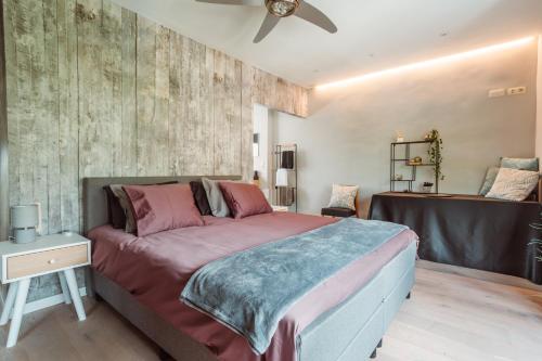 a bedroom with a large bed and a ceiling fan at De Visitor in Eeklo