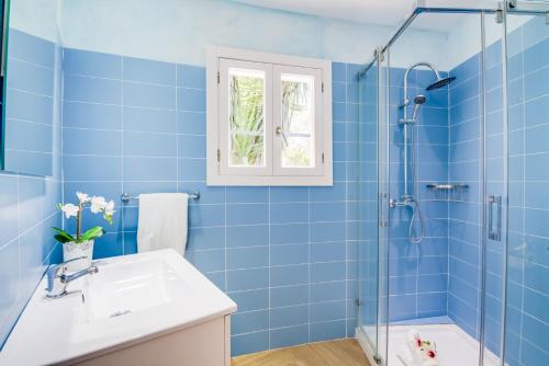 ein blaues Bad mit einem Waschbecken und einer Dusche in der Unterkunft Casa Encinar in Crestatx
