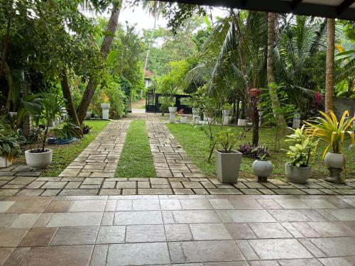 a garden with a pathway with potted plants and trees at Tanzanite place in Tangalle