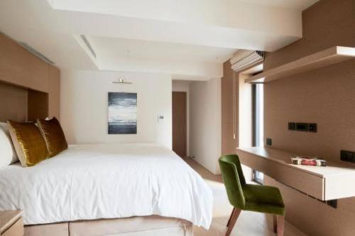 Maddox Street - 3 bed في لندن: غرفة نوم بسرير ابيض وكرسي اخضر