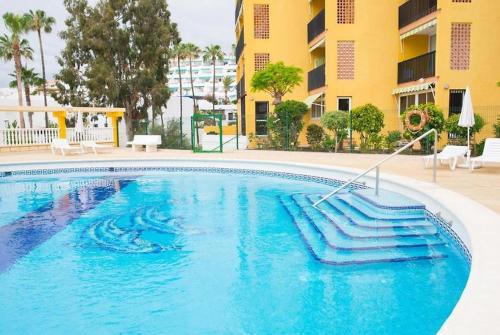 a swimming pool with blue water in front of a building at Apartment Las Americas in Playa de las Americas