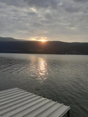 a view of a body of water with the sun setting at Cazanele Dunarii "La Cumatru" in Dubova