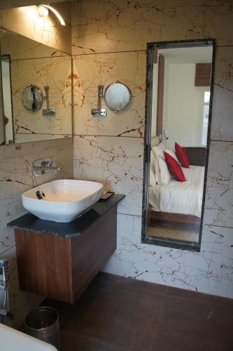 a bathroom with a sink and a mirror and a bed at LEELA BIZOTEL in Junagadh