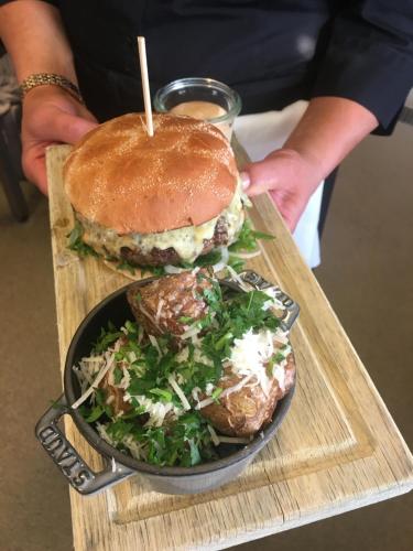 a person holding a sandwich and a plate of food at Fredriksborg Hotell & Restaurang in Värmdö