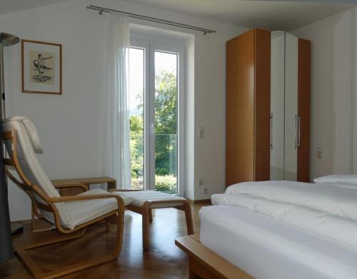 a bedroom with two beds and a chair and a window at Kaufhold Ferienwohnung in Immenstadt im Allgäu