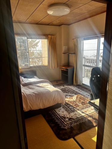 a small bedroom with a bed and a window at ペンションレークサイド in Otsu