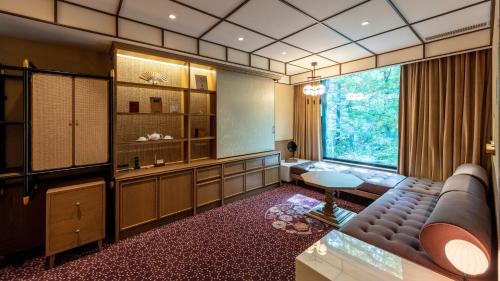 Zimmer mit Sofa, Tisch und Fenster in der Unterkunft Fufu Nikko in Nikko