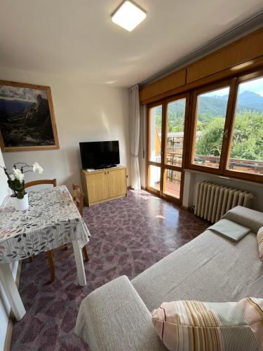 a living room with a bed and a table with a television at DOLOMITI HOUSE 6 in Fiera di Primiero