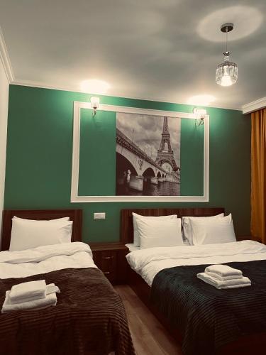 two beds in a room with a painting on the wall at Guesthouse Relax in Kazbegi in Stepantsminda