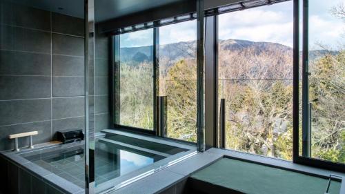 a bathroom with a glass shower with a view of the mountains at Fufu Hakone in Hakone