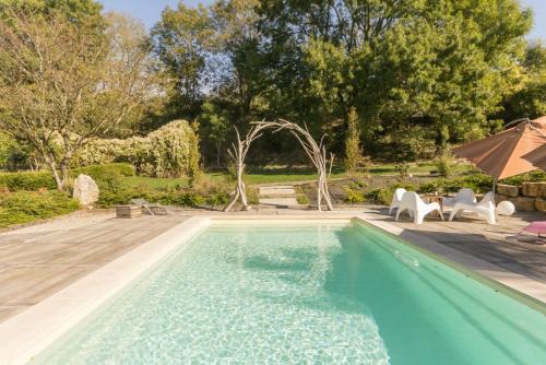 una piscina con sillas y sombrilla en LES DIVINES BOURGOGNE en La Rochepot