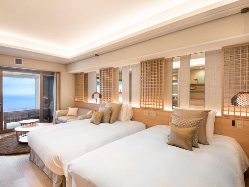 a hotel room with two beds and a couch at Atami Sekaie in Atami