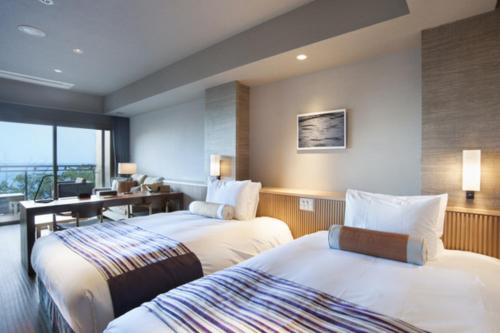 a hotel room with two beds and a desk at Atami Sekaie in Atami