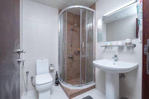 a bathroom with a shower and a toilet and a sink at Stunning 2BD Sea View Apartment Private Beach Access in Ras al Khaimah