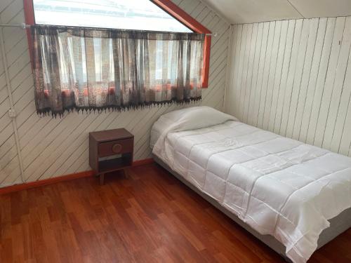 a small bedroom with a bed and a window at Hostal y Hospedaje Chacabuco in Castro