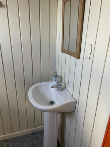 ein Badezimmer mit einem weißen Waschbecken und einem Spiegel in der Unterkunft Hostal y Hospedaje Chacabuco in Castro