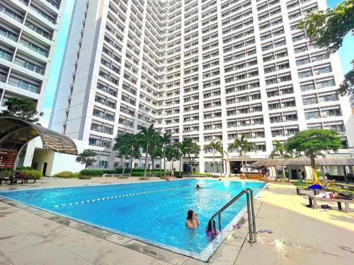 two people in a swimming pool with a large building at Stylish 1BR with Wifi and Queen size bed in Grace Res in Manila